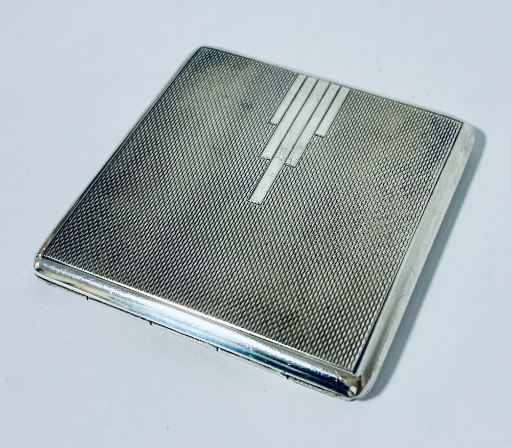 A square Art Deco silver powder compact with an engine-turned guilloche surface and a stepped geometric motif. View VII