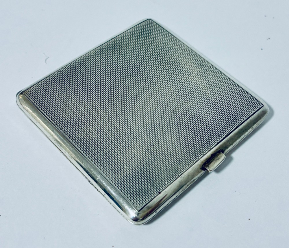 A square Art Deco silver powder compact with an engine-turned guilloche surface and a stepped geometric motif. View VIII