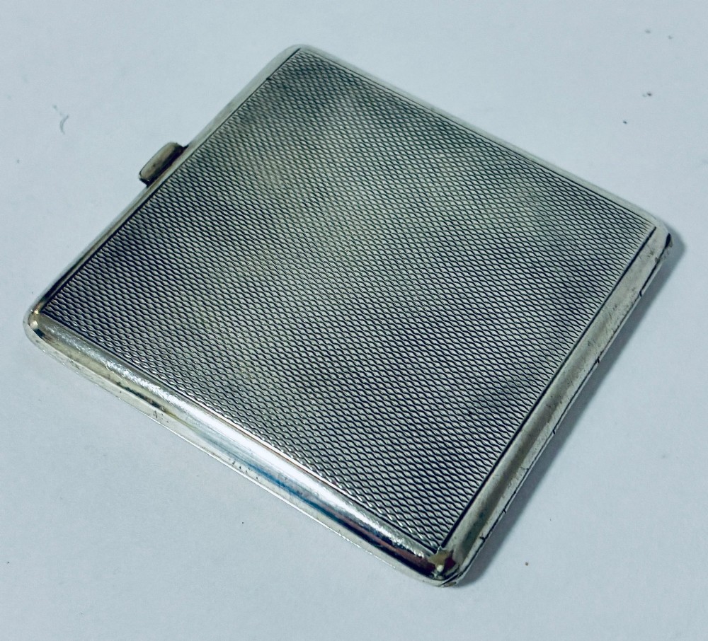 A square Art Deco silver powder compact with an engine-turned guilloche surface and a stepped geometric motif. View IX