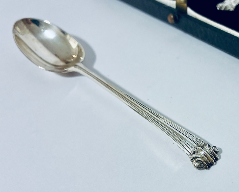 A set of six silver teaspoons with decorative reeded handles displayed inside an open fitted presentation case lined in dark velvet and white satin. View V