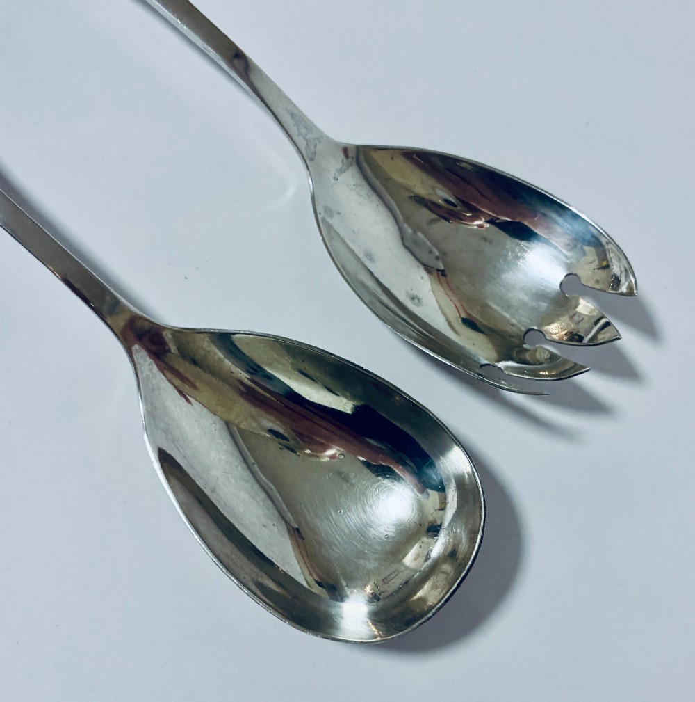 A pair of antique silver salad servers displaying planished hammered handles and polished metal serving ends. View II