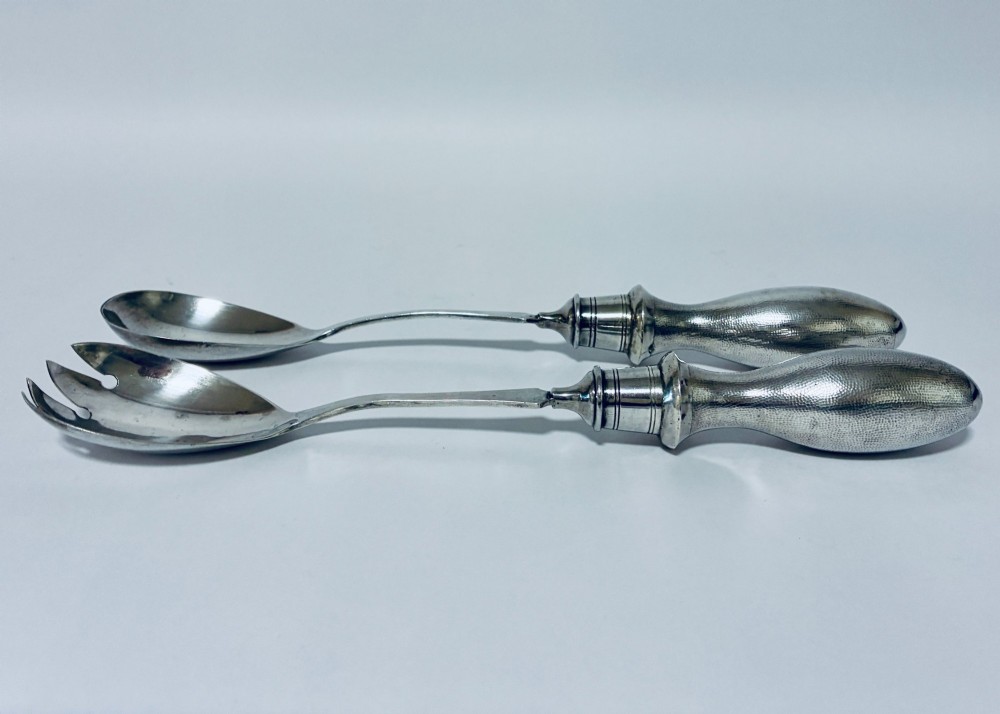 A pair of antique silver salad servers displaying planished hammered handles and polished metal serving ends. View IV