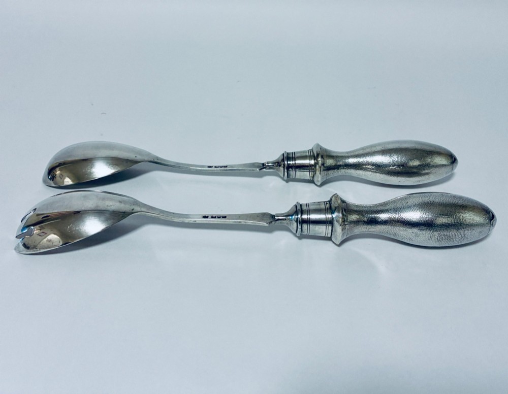 A pair of antique silver salad servers displaying planished hammered handles and polished metal serving ends. View VII