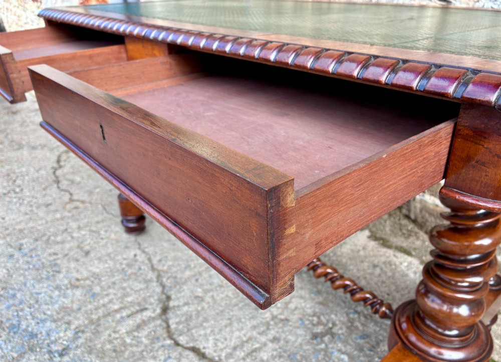 A Victorian walnut library writing table featuring a green inset leather top, carved gadrooned edge, twin drawers, and spiral barley twist legs connected by a central stretcher. View XI