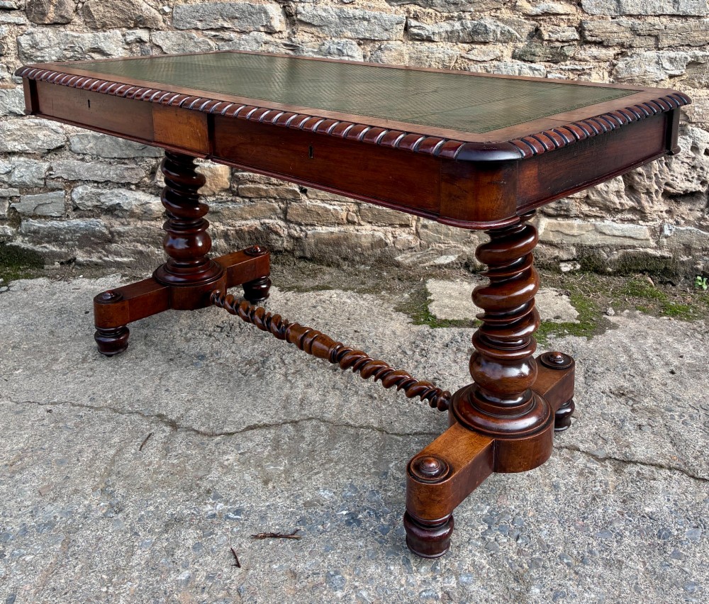 A Victorian walnut library writing table featuring a green inset leather top, carved gadrooned edge, twin drawers, and spiral barley twist legs connected by a central stretcher. View XII