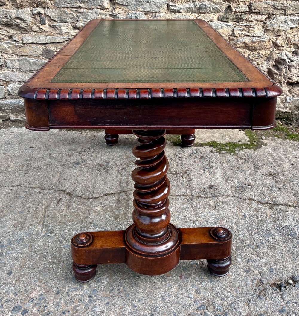 A Victorian walnut library writing table featuring a green inset leather top, carved gadrooned edge, twin drawers, and spiral barley twist legs connected by a central stretcher. View XIII