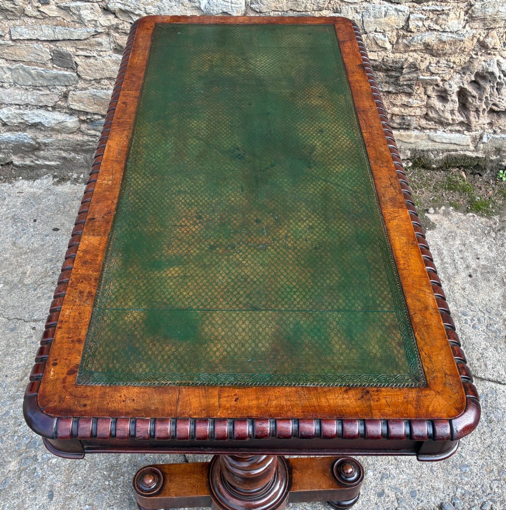 A Victorian walnut library writing table featuring a green inset leather top, carved gadrooned edge, twin drawers, and spiral barley twist legs connected by a central stretcher. View XIV