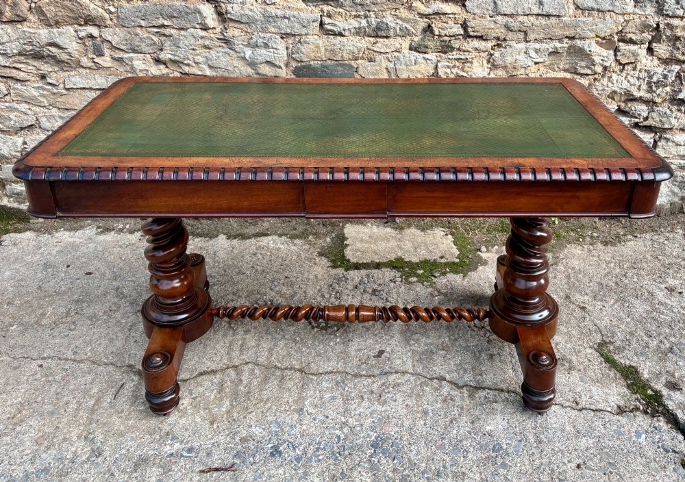 A Victorian walnut library writing table featuring a green inset leather top, carved gadrooned edge, twin drawers, and spiral barley twist legs connected by a central stretcher. View XV