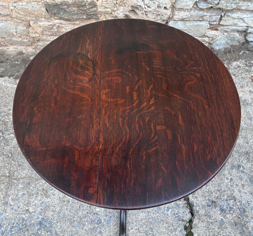 A dark brown Georgian oak tilt-top tripod table featuring a circular top, turned baluster column, and three cabriole legs. View III