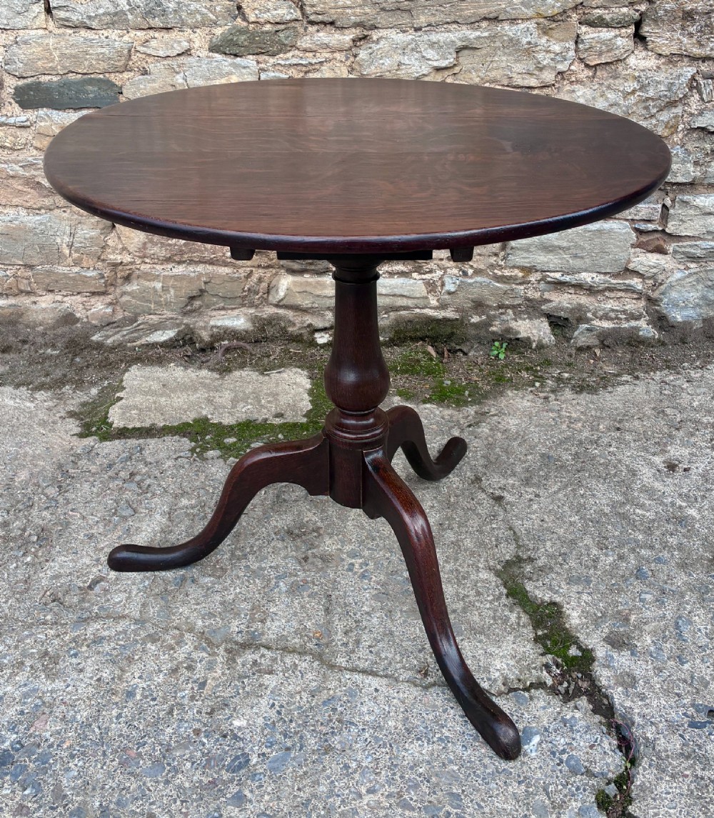 A dark brown Georgian oak tilt-top tripod table featuring a circular top, turned baluster column, and three cabriole legs. View IV