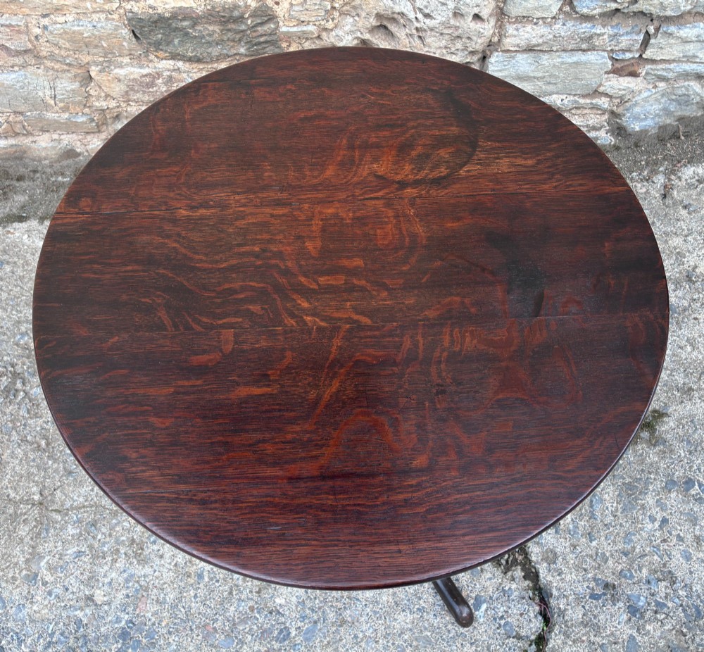 A dark brown Georgian oak tilt-top tripod table featuring a circular top, turned baluster column, and three cabriole legs. View V