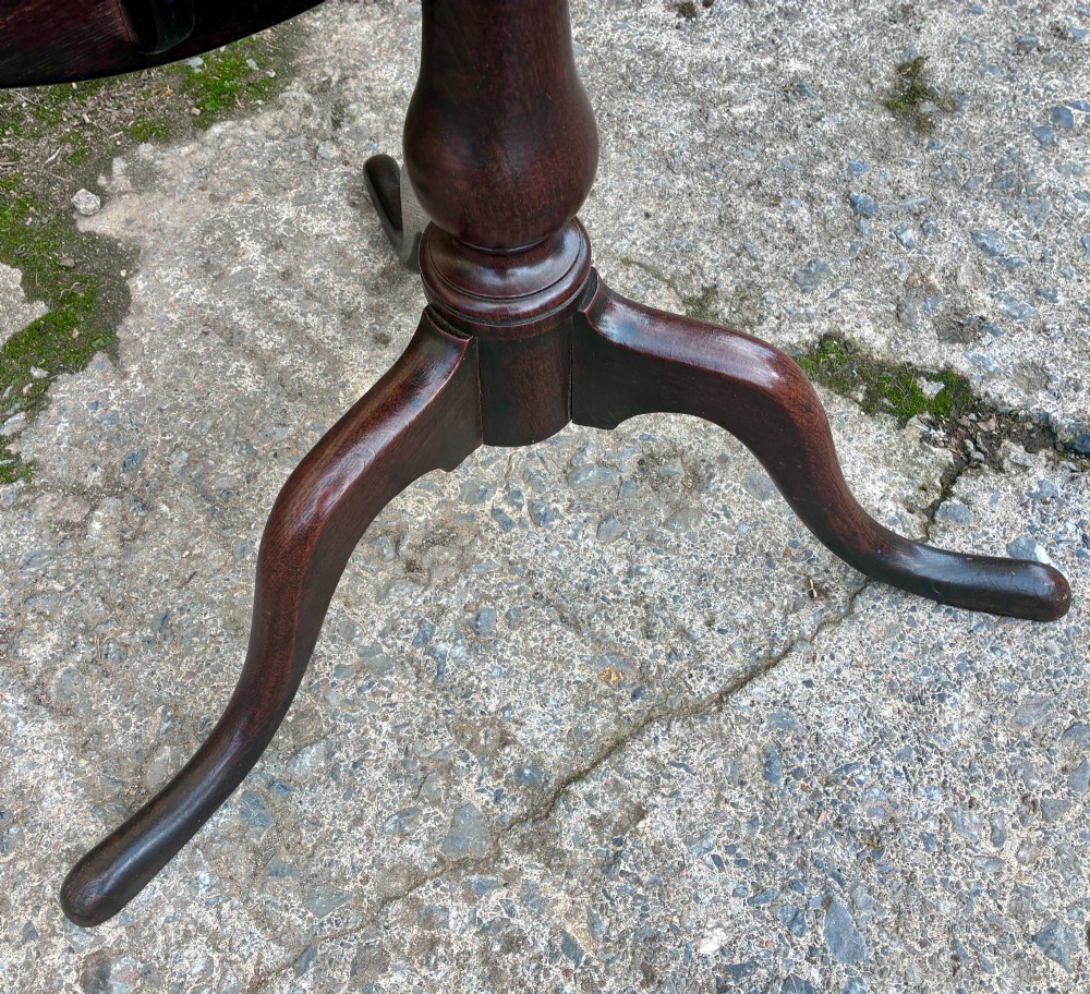 A dark brown Georgian oak tilt-top tripod table featuring a circular top, turned baluster column, and three cabriole legs. View IX