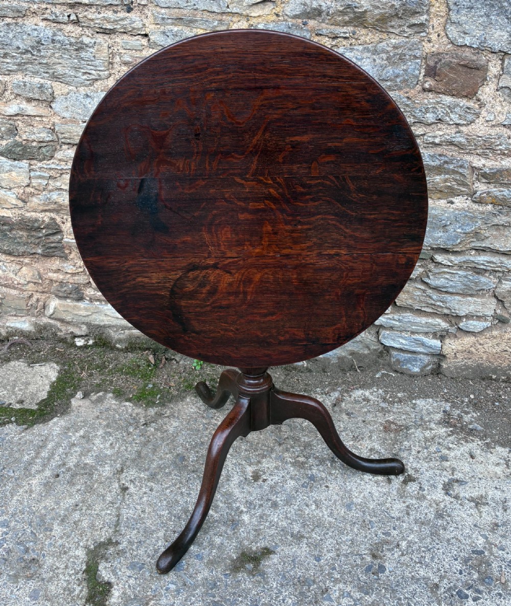 A dark brown Georgian oak tilt-top tripod table featuring a circular top, turned baluster column, and three cabriole legs. View XIII