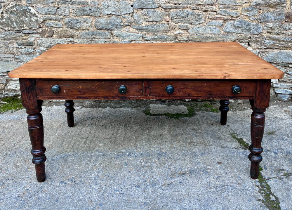 A Victorian pine farmhouse table featuring a light natural timber plank top, two frieze drawers with round wooden knobs, and four dark turned wooden legs.
