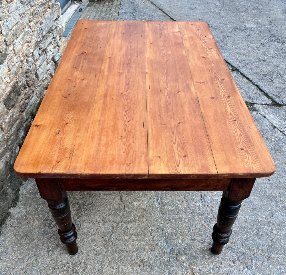 A Victorian pine farmhouse table featuring a light natural timber plank top, two frieze drawers with round wooden knobs, and four dark turned wooden legs. View V