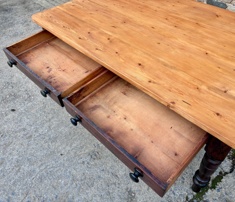 A Victorian pine farmhouse table featuring a light natural timber plank top, two frieze drawers with round wooden knobs, and four dark turned wooden legs. View VIII
