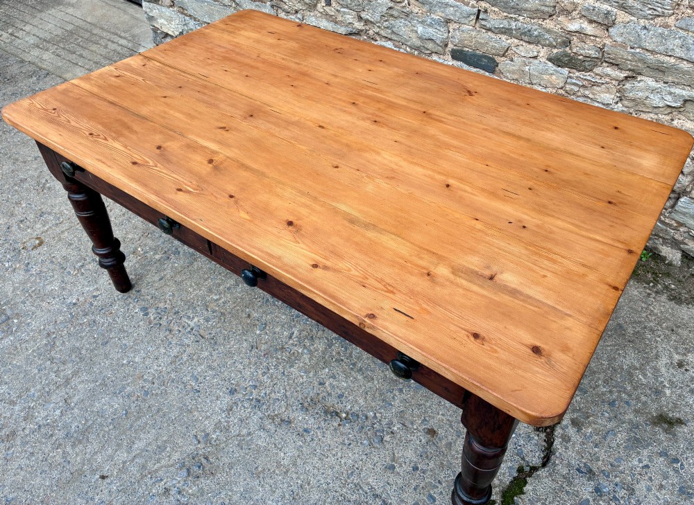 A Victorian pine farmhouse table featuring a light natural timber plank top, two frieze drawers with round wooden knobs, and four dark turned wooden legs. View X