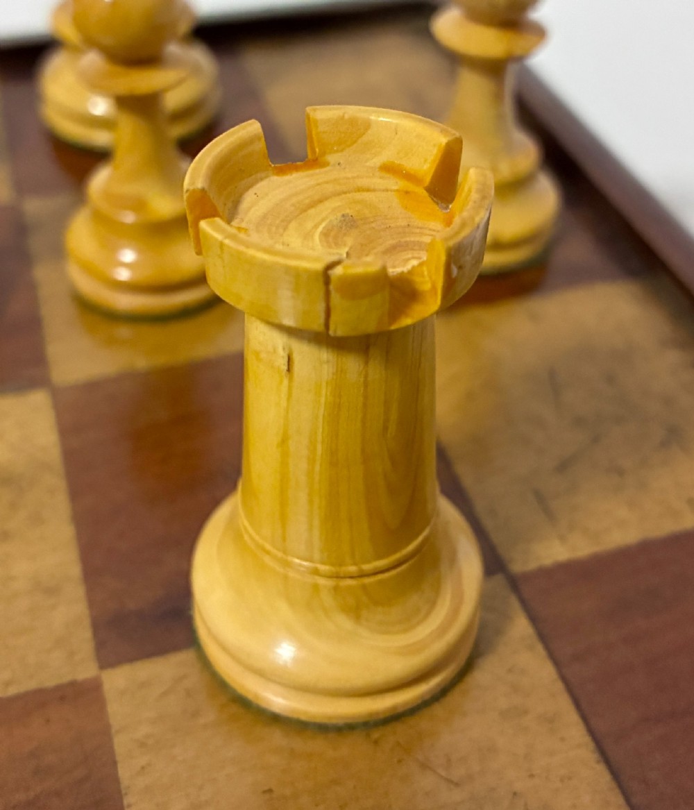 An antique hinged wooden folding games board with a checkerboard surface, accompanied by turned draughts counters and a sliding wooden box containing chess pieces. View XIII