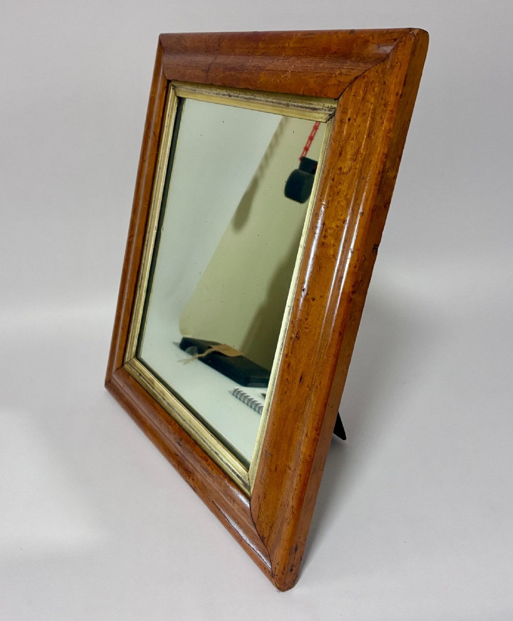 An antique rectangular birds eye maple frame featuring an inner gilt slip rim surrounding a mirror glass plate, supported by an easel stand. View V