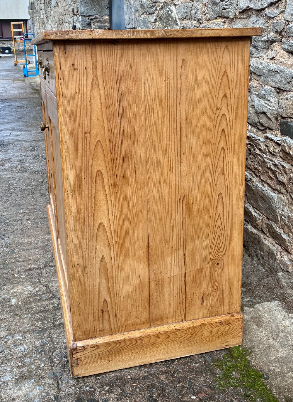 A nineteenth-century stripped pine sideboard featuring two upper drawers with ornate brass handles above two panelled cupboard doors on a solid plinth base. View VII
