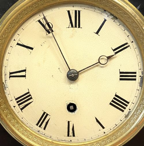 fig 3. An antique ebonised wooden mantel clock featuring ornate cast ormolu mounts, a white dial with Roman numerals, and scrolled gilt brass feet.