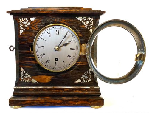fig 2. An antique coromandel wood mantel clock featuring mother-of-pearl corner inlays, a round brass bezel, and a silvered dial with Roman numerals.
