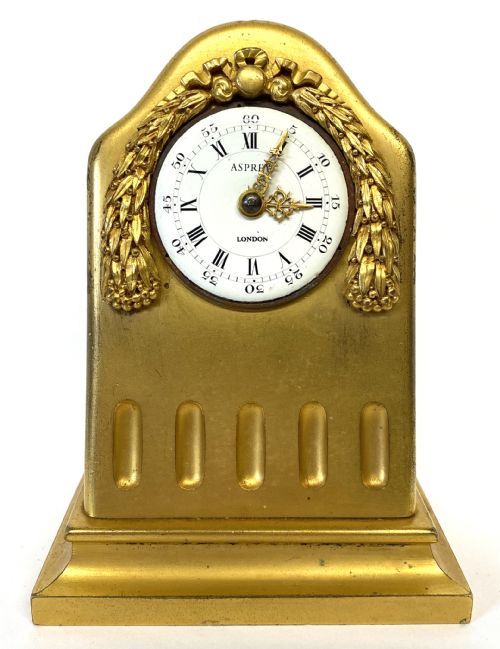 fig 1. An arched gilt bronze desk clock with carved laurel garland details and a white enamel dial marked Asprey London.