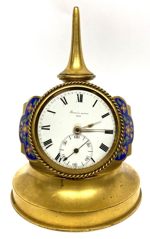 fig 1. An antique gilt bronze desk clock featuring a white enamel dial with Roman numerals, flanked by blue floral champleve enamel wings and topped with a tapered finial.