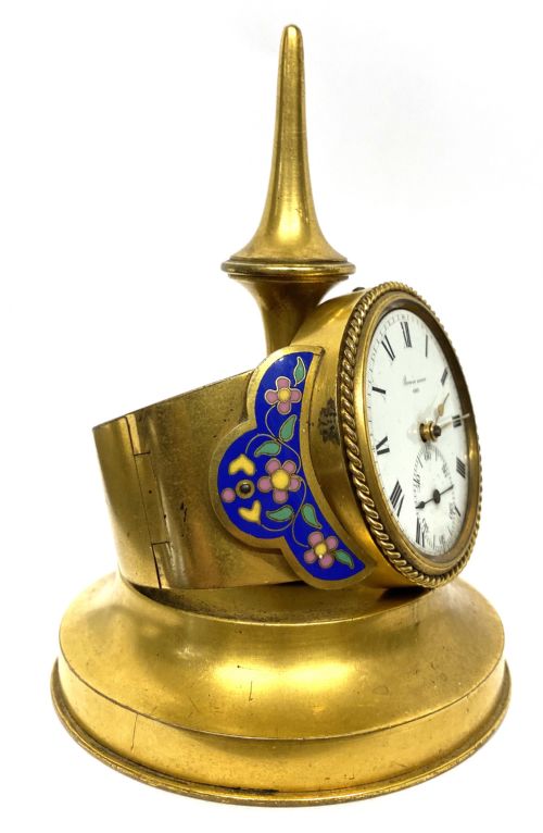 fig 2. An antique gilt bronze desk clock featuring a white enamel dial with Roman numerals, flanked by blue floral champleve enamel wings and topped with a tapered finial.