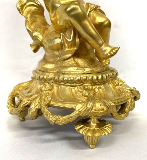 fig 2. A gilt bronze Victorian mantel clock featuring a sculpted cherub supporting a circular white enamel clock dial signed John Bennett London.