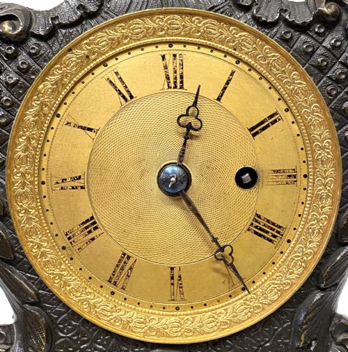 fig 1. An antique miniature bronze mantel clock featuring Rococo scrollwork, cabriole legs, and an engraved gold-tone brass dial with Roman numerals.