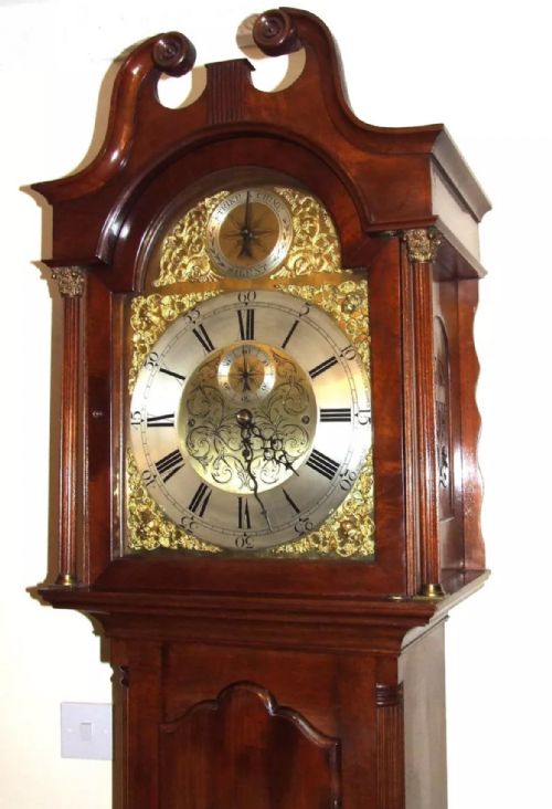 fig 3. A mahogany longcase grandfather clock featuring a swan-neck pediment, brass dial with Roman numerals, and a polished timber cabinet.