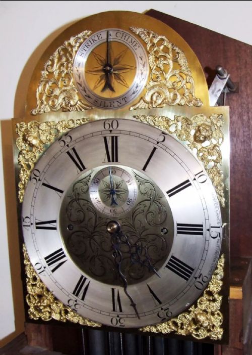 fig 4. A mahogany longcase grandfather clock featuring a swan-neck pediment, brass dial with Roman numerals, and a polished timber cabinet.