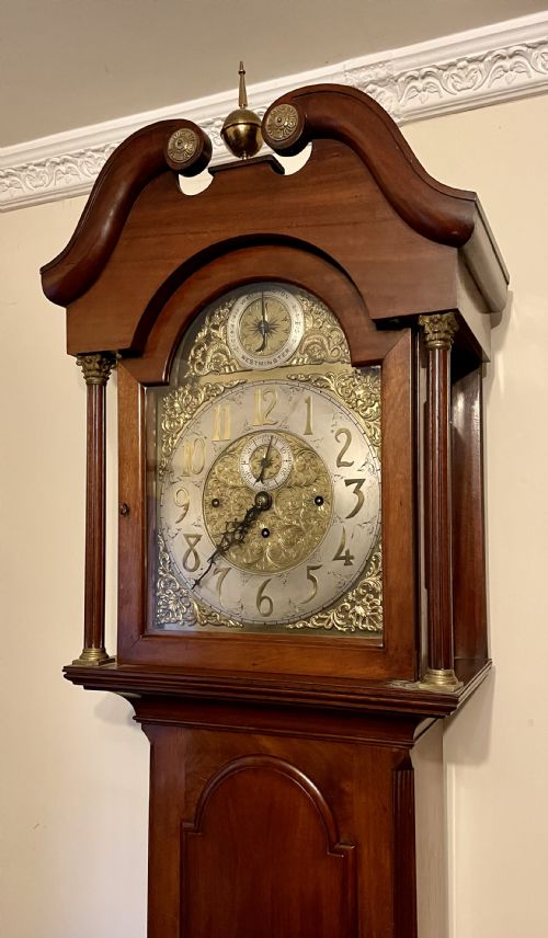 fig 2. A mahogany longcase clock featuring a swan-neck pediment, brass arch dial with silvered chapter ring, fluted columns, and a shaped trunk door.