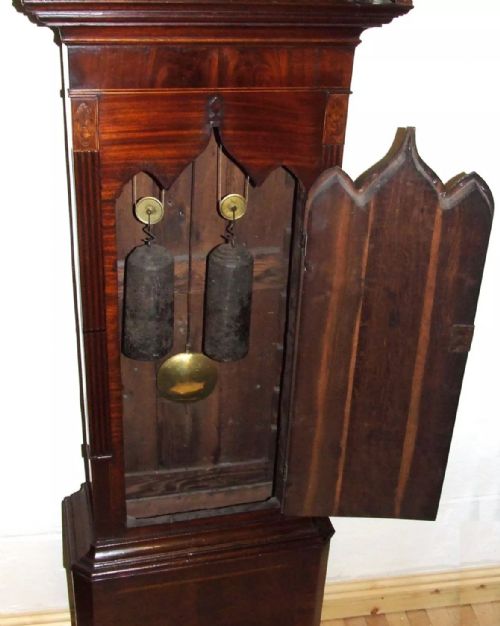 fig 8. An antique mahogany longcase grandfather clock featuring a painted arched dial with a moon phase indicator, swan neck pediment, and flame mahogany inlaid cabinet door.