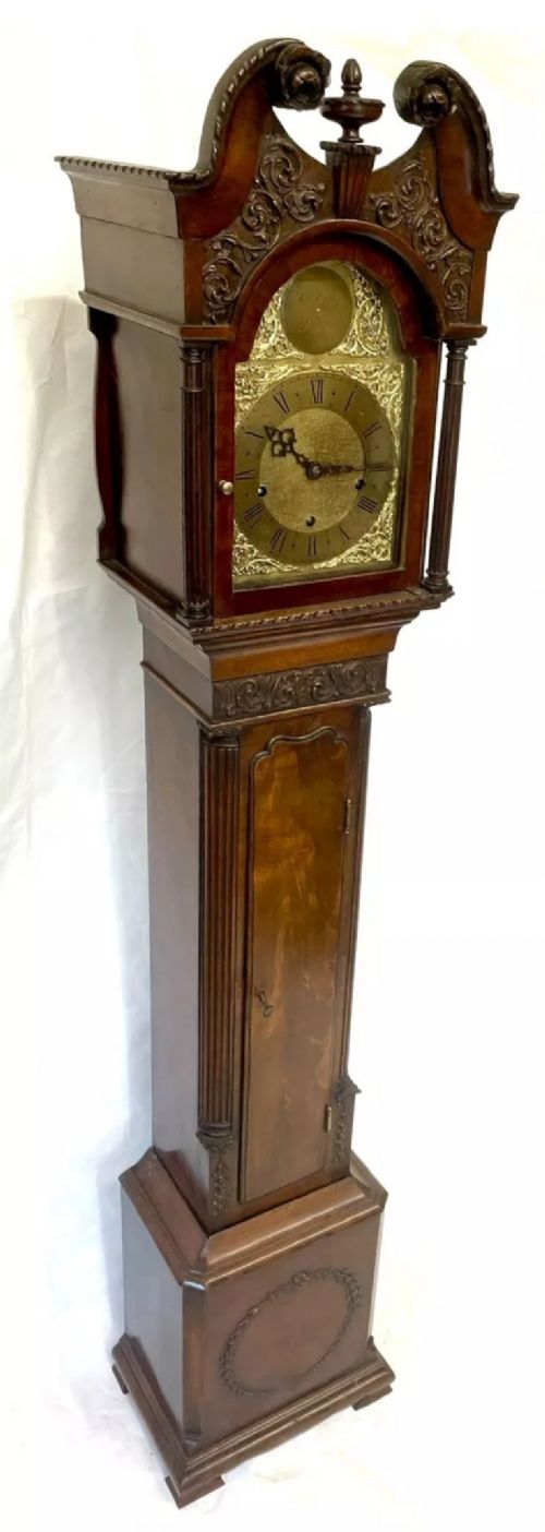 fig 2. An antique mahogany grandmother clock featuring a swan-neck pediment, carved scrollwork details, fluted columns, and an ornate brass dial with Roman numerals.