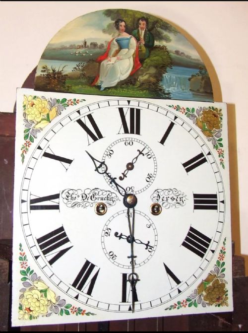 fig 4. An antique inlaid mahogany longcase clock featuring a swan-neck pediment with finials, a painted arch dial, and twisted side columns.