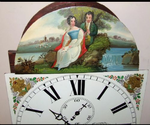 fig 5. An antique inlaid mahogany longcase clock featuring a swan-neck pediment with finials, a painted arch dial, and twisted side columns.