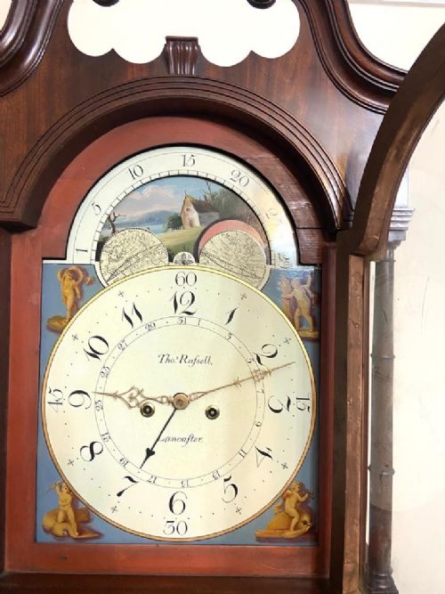 fig 8. A Georgian flame mahogany longcase clock featuring a swan-neck pediment, turned columns, and a painted dial with a rolling moon phase mechanism.