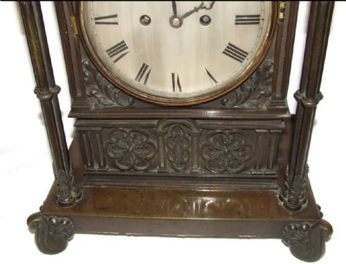fig 4. A dark brown patinated bronze mantel clock featuring Gothic architectural columns, decorative relief carvings, scroll feet, and a silvered circular dial with Roman numerals.