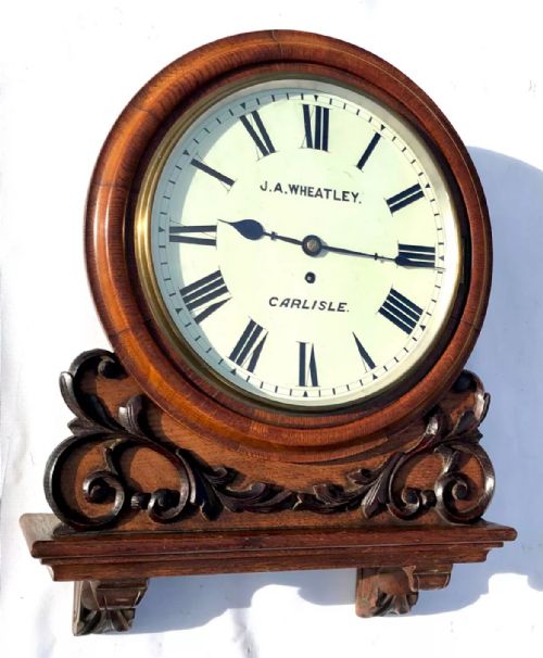 fig 1. Victorian mahogany circular fusee wall clock with carved scrollwork base and a white dial signed J. A. Wheatley Carlisle.