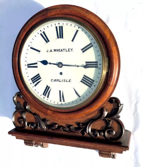 fig 2. Victorian mahogany circular fusee wall clock with carved scrollwork base and a white dial signed J. A. Wheatley Carlisle.