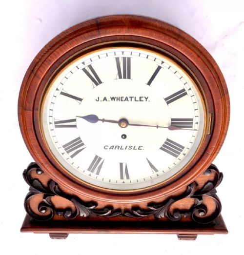 fig 4. Victorian mahogany circular fusee wall clock with carved scrollwork base and a white dial signed J. A. Wheatley Carlisle.