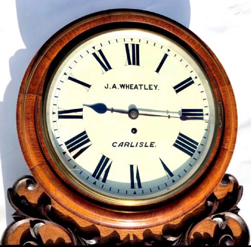 fig 5. Victorian mahogany circular fusee wall clock with carved scrollwork base and a white dial signed J. A. Wheatley Carlisle.