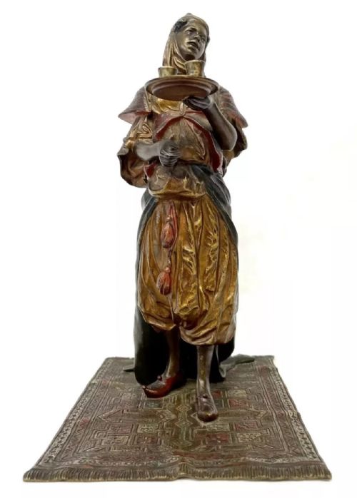 fig 2. An antique cold-painted bronze statuette depicting an Arab woman carrying a tea tray while standing on an engraved rug base.