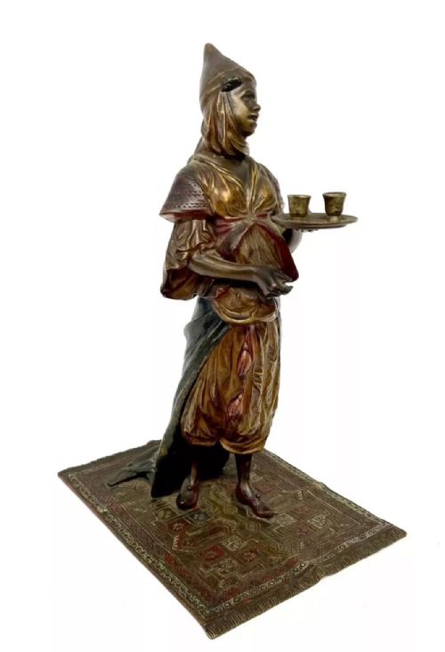 fig 3. An antique cold-painted bronze statuette depicting an Arab woman carrying a tea tray while standing on an engraved rug base.