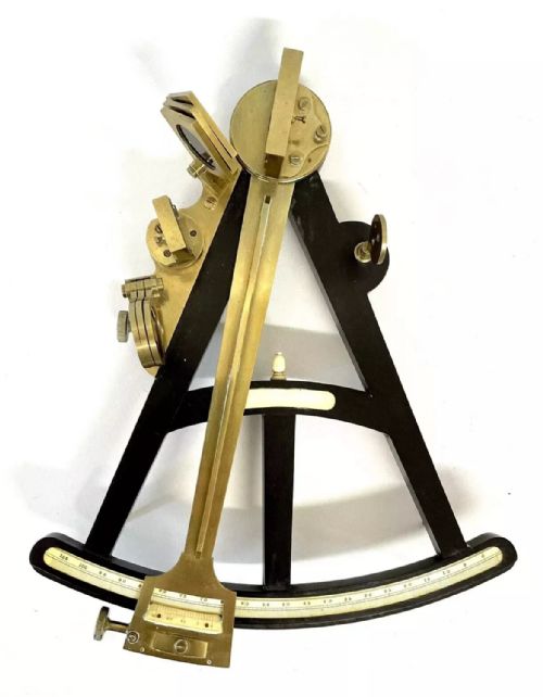 fig 2. An antique brass and ebony marine octant with an inlaid arc scale, set inside an open keystone-shaped mahogany carrying case with a paper maker label.