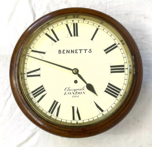 fig 1. An antique circular mahogany wall clock featuring an off-white dial with black Roman numerals, brass bezel, and Bennetts Cheapside London inscription.