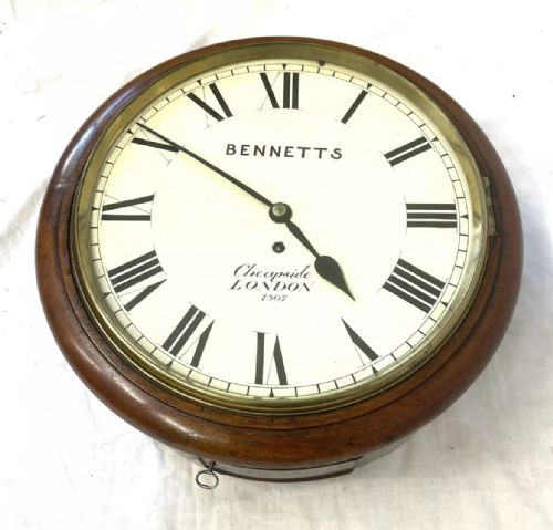 fig 2. An antique circular mahogany wall clock featuring an off-white dial with black Roman numerals, brass bezel, and Bennetts Cheapside London inscription.