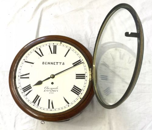 fig 5. An antique circular mahogany wall clock featuring an off-white dial with black Roman numerals, brass bezel, and Bennetts Cheapside London inscription.